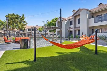 a yard with two hammocks and some apartments in the background